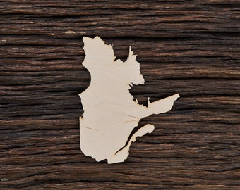 May include: A wooden cutout of the province of Quebec, Canada, on a dark brown wooden background.