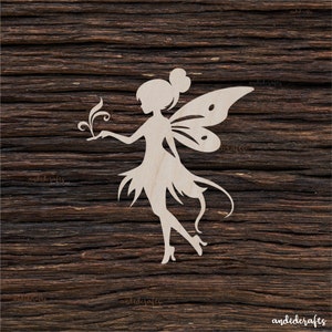 Peut inclure: Une découpe en bois blanc d'une fée avec des ailes, tenant une fleur dans sa main. La fée est debout sur un fond en bois.