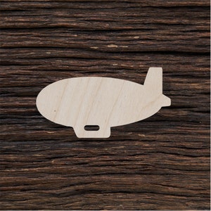 May include: A wooden cutout of a blimp, a type of airship, on a brown wooden background.