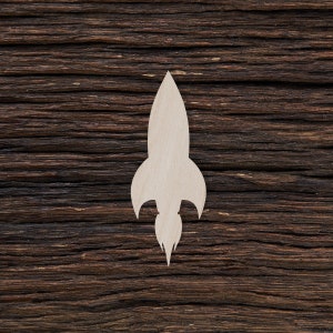May include: A white wooden rocket ship cutout on a dark brown wood background.