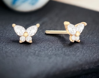 May include: A pair of gold butterfly earrings with clear cubic zirconia stones.