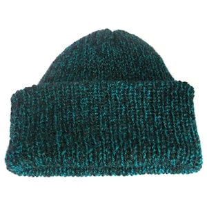 Peut inclure: Un bonnet tricot&eacute; de couleur sarcelle et noir. Le bonnet a un bord c&ocirc;tel&eacute; et est fait d'un fil &eacute;pais et textur&eacute;. Le bonnet est de couleur unie avec un subtil effet chin&eacute;, parfait pour le froid.