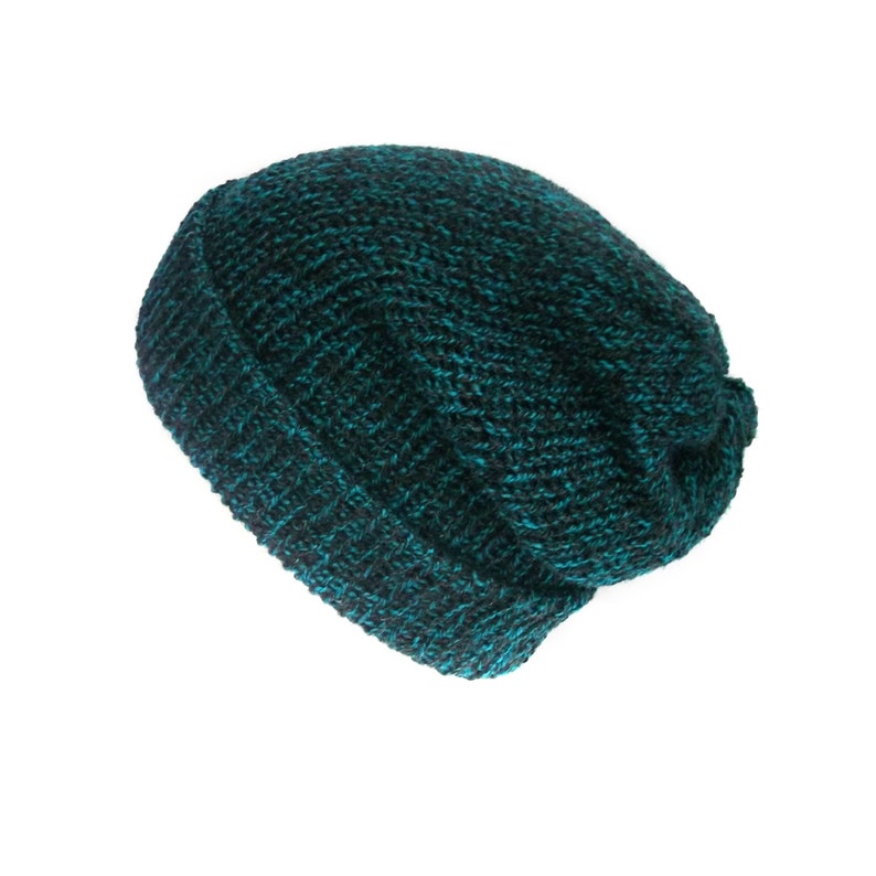 Peut inclure: Un bonnet en tricot de couleur teal et noir. Le bonnet est fait d'un fil &eacute;pais et textur&eacute; et poss&egrave;de un bord repli&eacute;. La couleur est un m&eacute;lange de teal et de noir, cr&eacute;ant un effet mouchet&eacute;. Le bonnet est con&ccedil;u pour &ecirc;tre port&eacute; sur la t&ecirc;te.