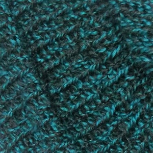 Peut inclure: Gros plan sur un tissu textur&eacute; avec des fils bleu sarcelle et gris fonc&eacute;. Le mat&eacute;riau tricot&eacute; pr&eacute;sente une texture dense et boucl&eacute;e, cr&eacute;ant un aspect doux et moelleux. La combinaison de couleurs offre un aspect riche et dimensionnel, adapt&eacute; &agrave; divers projets textiles.