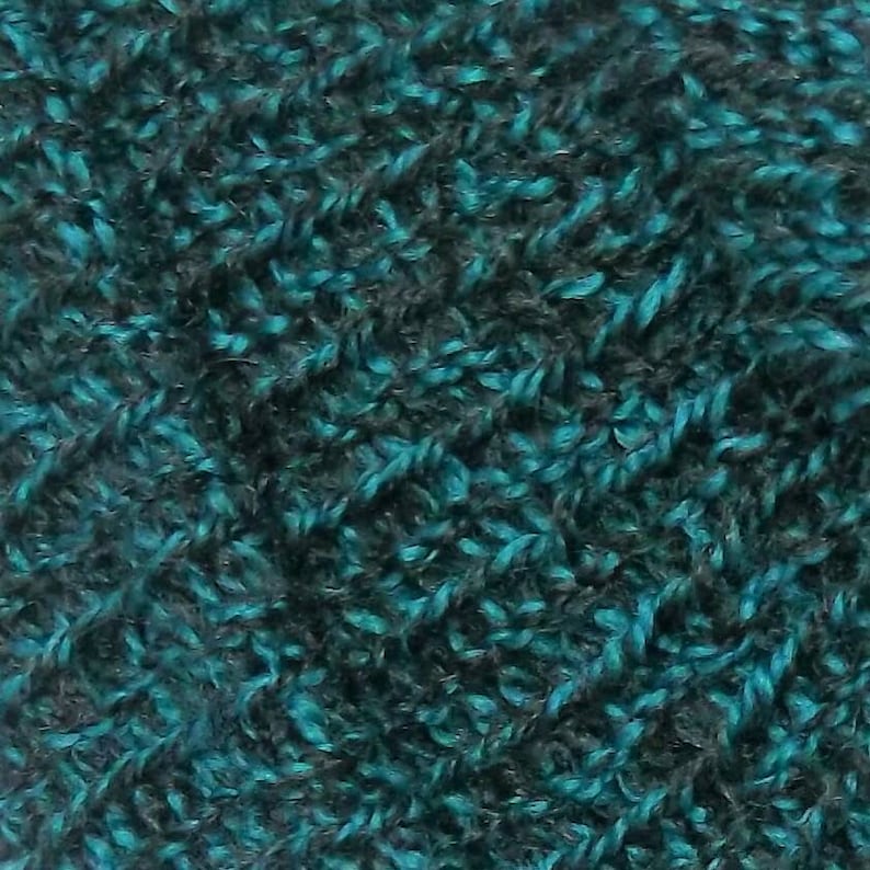 Peut inclure: Gros plan sur un tissu textur&eacute; avec des fils bleu sarcelle et gris fonc&eacute;. Le mat&eacute;riau tricot&eacute; pr&eacute;sente une texture dense et boucl&eacute;e, cr&eacute;ant un aspect doux et moelleux. La combinaison de couleurs offre un aspect riche et dimensionnel, adapt&eacute; &agrave; divers projets textiles.