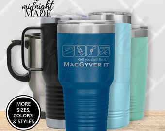 May include: A blue stainless steel tumbler with a white inscription that reads "If you can't fix it, MACGYVER IT". The tumbler has a black lid and a black handle. The inscription also includes four icons of tools: tape, paperclip, rope, and a wrench.