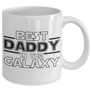 May include: White ceramic coffee mug with black text that reads "Best Daddy in the Galaxy".