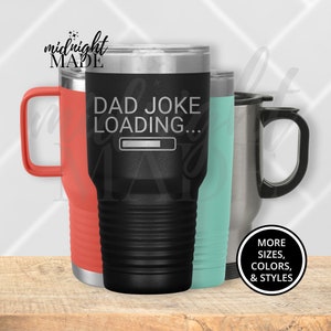 May include: A black stainless steel tumbler with a white inscription that reads "Dad Joke Loading..." with a progress bar. The tumbler is surrounded by two other tumblers, one red and one light blue.