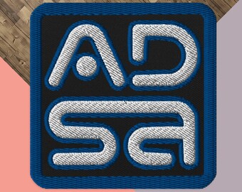 May include: A blue and white embroidered patch with the text "ADSA" in white letters on a blue background.