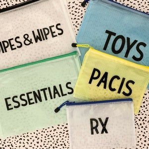 May include: Five mesh zippered pouches with different colored borders and labels. The labels read "Diapers & Wipes", "Essentials", "Pacis", "Toys", and "RX".