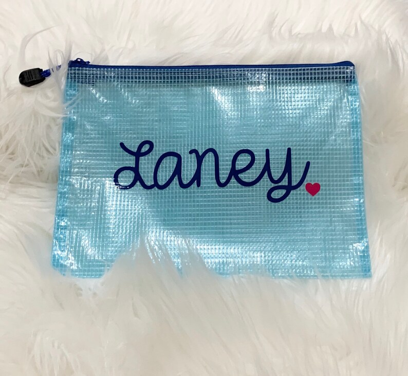 Puede incluir: Una bolsa de malla azul claro con cremallera azul marino y el nombre "Laney" bordado en azul marino con un coraz&oacute;n rojo.