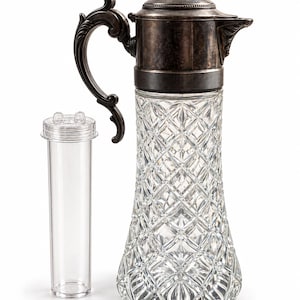 Puede incluir: Una jarra de cristal transparente con patrón de diamante y una tapa y asa de metal plateado oscuro y desgastado. Junto a la jarra hay un inserto cilíndrico de plástico transparente con una tapa pequeña que tiene dos pestañas.