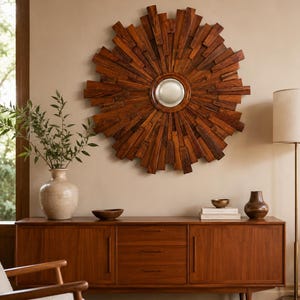 May include: A circular wall mirror featuring a sunburst frame constructed from numerous rectangular pieces of dark brown wood arranged in a radiating pattern around a small, smooth, reflective center mirror with a metallic silver border.