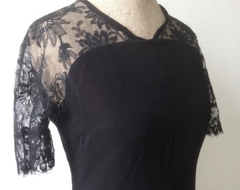 May include: A black dress with short sleeves made of lace. The dress has a v-neckline and a fitted silhouette.