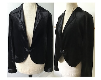 May include: A black velvet cropped jacket with a shawl collar and a single button fastening.