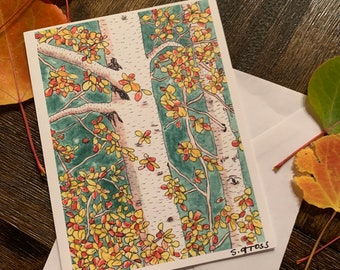 May include: A greeting card featuring a watercolor illustration of birch trees with yellow and red autumn leaves. The card is inside a white envelope, with fall leaves scattered around it. The artist's signature, "S. Gross," is visible.