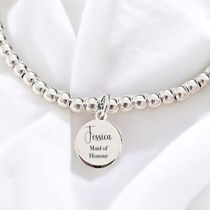 May include: Silver beaded bracelet with a charm that says "Jessica Maid of Honour".
