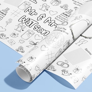 May include: A roll of white wrapping paper with a black and white wedding design. The paper features illustrations of cakes, champagne glasses, hearts, and the text "Mr & Mrs Watson". The paper is unrolled on a light blue surface.