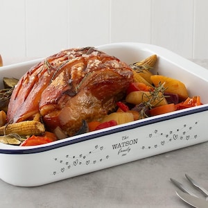 May include: White enamel baking dish with a blue rim, filled with roasted vegetables and a pork roast. The dish has a black and white design with the text "The Watson Family".