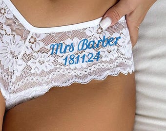 May include: White lace underwear with floral patterns. The text "Mrs Barber 18.11.24" is embroidered in blue on the front. The underwear has a low-rise cut and delicate lace trim.