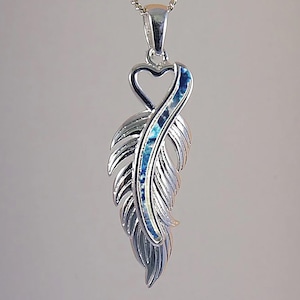 May include: Silver feather pendant necklace with a blue and white inlay. The pendant has a heart-shaped bail and hangs from a delicate chain. The feather design has detailed edges.