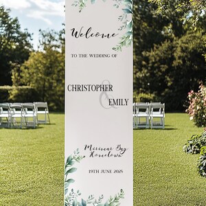 May include: A rectangular wedding sign with a white background and green botanical illustrations. The sign says "Welcome to the Wedding of Christopher & Emily", with the location and date, 19th June 2025. The sign is on a lawn.