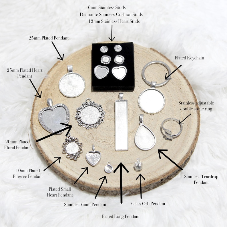 May include: A collection of jewelry findings, including pendants, studs, a keychain, and a ring, displayed on a wooden slice. The pieces are silver-toned and come in various shapes and sizes, such as hearts, circles, and teardrops.