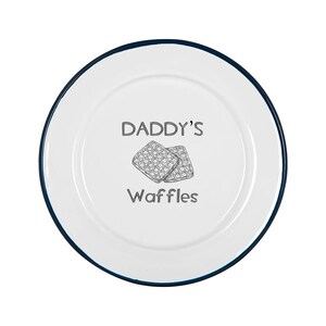 May include: White plate with a dark blue rim featuring the text "DADDY'S Waffles" and a graphic of two waffles. The plate is round and has a clean, minimalist design, perfect for breakfast.