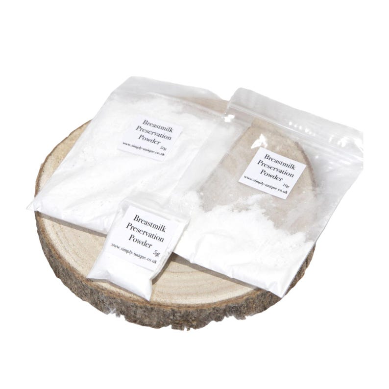 May include: Three clear plastic bags filled with white powder, labeled "Breastmilk Preservation Powder" in black text. The bags are arranged on a round, wooden slice. The smallest bag contains 5g of powder, while the larger bags contain 10g and 30g.