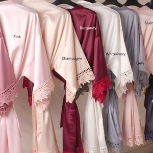 May include: Nine satin robes with lace trim in various colours, including dusty rose, pink, champagne, burgundy, white/ivory, grey, blush, and navy.