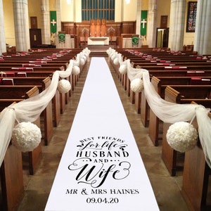Peut inclure: Un chemin de cérémonie blanc avec du texte noir qui dit "Best Friends for Life Husband and Wife" avec les noms "Mr. & Mrs. Haines" et la date "09.04.20". Le chemin de cérémonie est dans une église avec de la tulle blanche et des boules de fleurs blanches qui bordent l'allée.