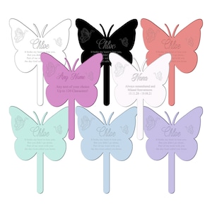 Pode incluir: Um conjunto de dez estacas de jardim comemorativas de borboleta em várias cores, incluindo branco, preto, rosa, azul claro e verde claro. Cada estaca apresenta uma silhueta de borboleta com uma mensagem personalizada, como "Chloe" ou "Nana". A mensagem "It broke my heart to lose you, but you didn't go alone. Part of me went with you the day God called you home" está incluída em várias das estacas.
