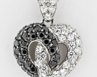 Puede incluir: Un collar de plata con un colgante en forma de corazón. El corazón está hecho de dos círculos entrelazados, uno engastado con diamantes blancos y el otro con diamantes negros.