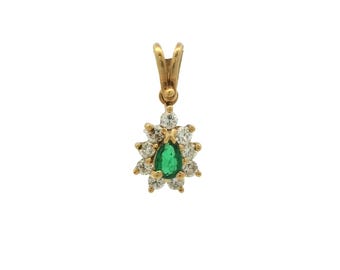 Puede incluir: Colgante de oro con una esmeralda verde en forma de pera, rodeada por un halo de pequeños diamantes brillantes. El colgante tiene una argolla para sujetarlo a una cadena. Un diseño elegante.
