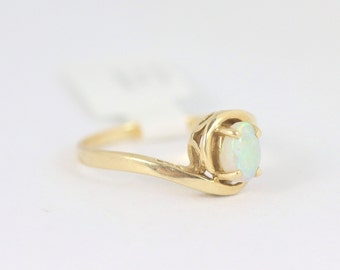 May include: A gold ring with a white opal gemstone set in a delicate, ornate design.