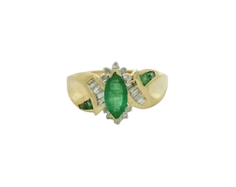 May include: A gold ring featuring a marquise-cut emerald center stone, surrounded by small diamonds and baguette-cut diamonds. The ring has a textured gold band and additional emerald accents on the sides.