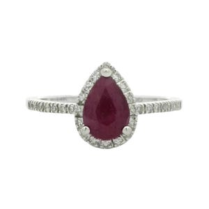 Peut inclure: Une bague en or blanc avec un rubis en forme de poire et un halo de petits diamants. La bague a une bande délicate.