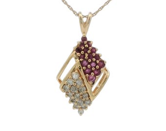 Op de afbeelding: Een gouden ketting met een geometrische hanger met een cluster van rode robijnen en een cluster van witte diamanten.