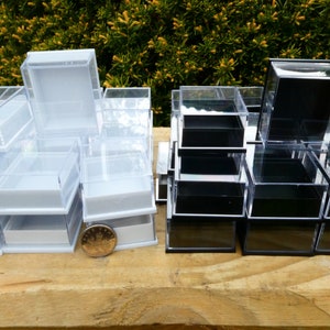 May include: Two stacks of clear plastic boxes with lids. The boxes on the left are white and the boxes on the right are black.