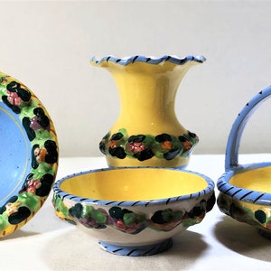 May include: A collection of hand-painted ceramic decorative pieces. Includes a blue bowl with a yellow rim, a yellow vase, a small bowl, and a basket with a handle. All pieces have floral and leopard print accents.