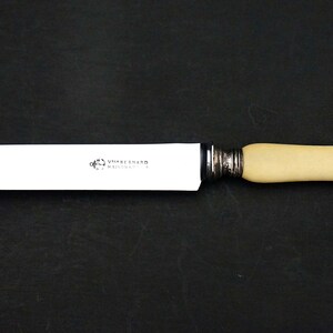 Puede incluir: Un cuchillo de mantequilla con mango blanco y hoja plateada. El mango es de hueso y tiene la inscripci&oacute;n "Shepherd  Sheffield".
