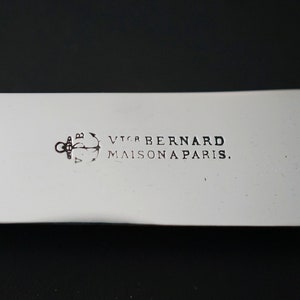 Puede incluir: Primer plano de un cuchillo de plata con mango negro. El cuchillo est&aacute; grabado con el texto "Victor Bernard Maison a Paris." y un ancla.