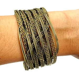 May include: A gold-toned woven wire bracelet with multiple strands of wire twisted together.