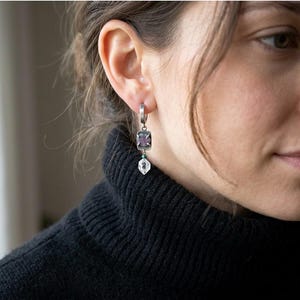 May include: A white ceramic mug with a black handle and the text "But First, Coffee" in a black, bold font. The mug is on a white surface.