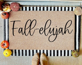 May include: A brown doormat with black and white stripes around the edges. The doormat has the text "Fall-elijah" written in black cursive font.