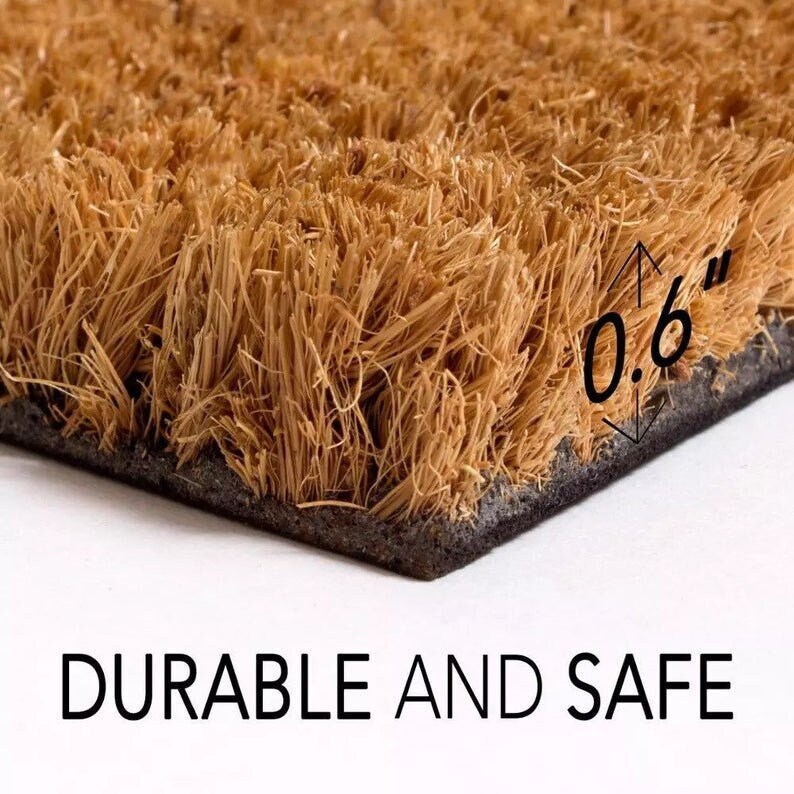 May include: Close-up of a brown coir doormat with a black backing. The mat is 0.6 inches thick. The text "DURABLE AND SAFE" is printed below the mat.