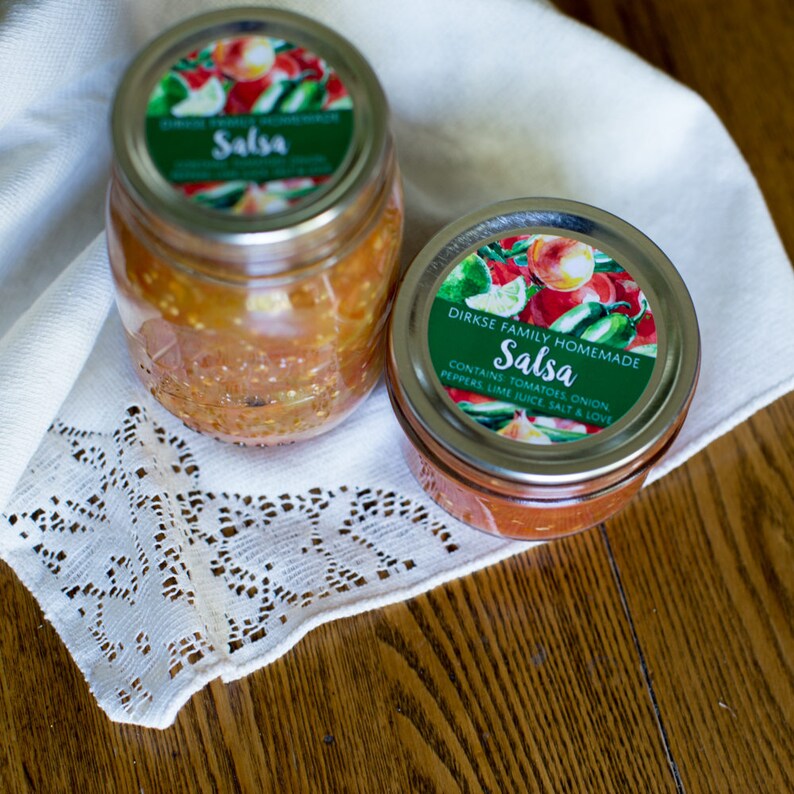 May include: Two glass jars filled with salsa, both with green and white labels that say "Salsa". The label on the smaller jar also says "Dirkse Family Homemade" and lists the ingredients.