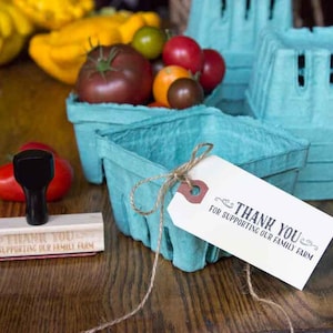 May include: A blue paperboard produce basket with a brown twine bow and a white tag that reads 