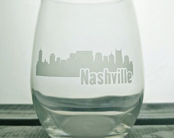 May include: A clear glass wine glass with an etched design of the Nashville skyline and the word "Nashville" below it.