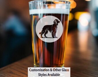 May include: A clear glass pint glass with a brown beer inside. The glass has a white circle with a black silhouette of a dog on it. The text "Customization & Other Glass Styles Available" is below the glass.